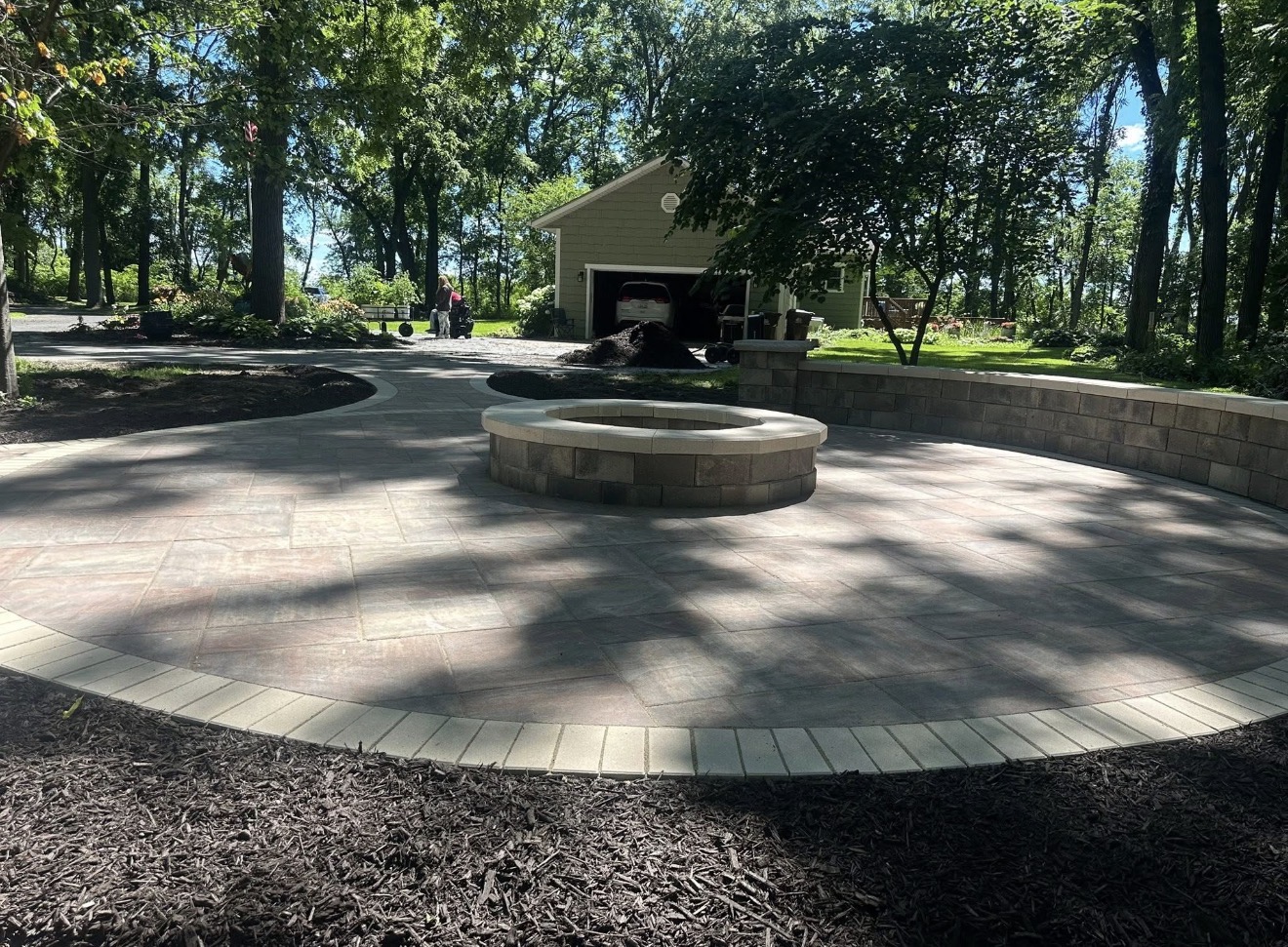 Circular paver patio with stone fire pit and seat wall