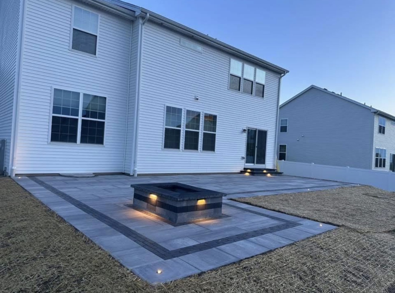 Modern rectangular paver patio with lit fire pit